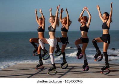 Group of girls doing exercises in kangoo jumping boots on seaside