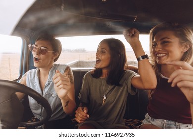 Group Of Girls Having Fun In The Car. Women Friends Singing Songs And Dancing In Car During Road Trip.