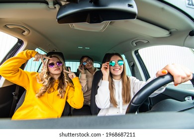 Group Of Girls Having Fun In The Car. Women Friends Singing Songs And Dancing In Car During Road Trip.