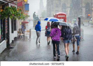 Group Of Girls Hurry At The Rain With Umbrella In The City