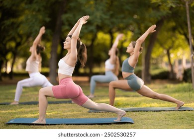 Group of girls in park practicing yoga outdoors. Active pastime together, performing exercises. Yoga lesson visitors perform ardha virabhadrasana. Girls practice sports during yoga workout in nature