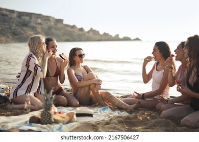 group of girls sitting on the beach eat fruit - Shutterstock ID 2167506427
