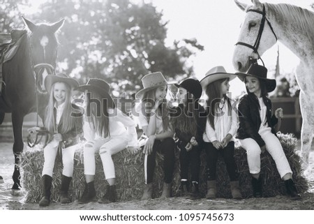 Group of girls sitting on hay with horses