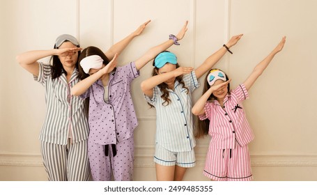 Group of girls in striped pajamas doing the dab pose. Pajama party. Atmosphere of the celebration - Powered by Shutterstock