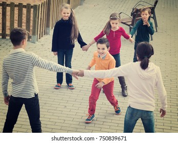 Group Of Glad Children Playing Red Rover Outdoors