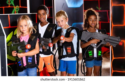 Group of glad pleasant teenagers with laser guns having fun on dark lasertag arena. High quality photo