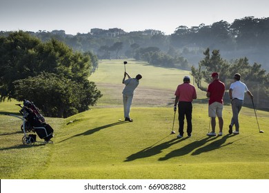 group of golfers playing  for pleasure , one of then hitting the ball with the golf club