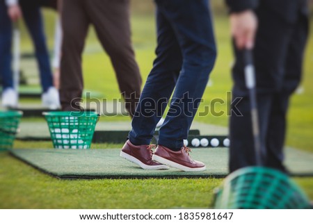 Group of golfers practicing and training golf swing on driving range practice, men playing on golf course, golf ball at golfing complex club resort 