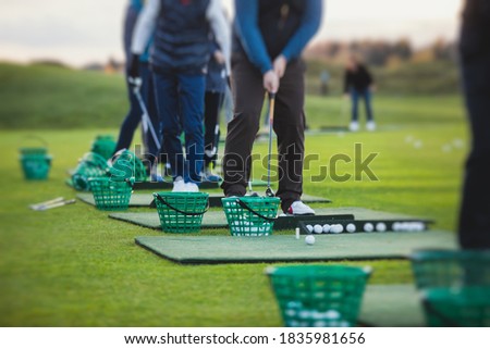 Group of golfers practicing and training golf swing on driving range practice, men playing on golf course, golf ball at golfing complex club resort 