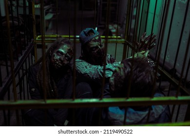 Group Of Gory Zombies Trapped In Cage In Dark Industrial Setting, FX Makeup, Copy Space