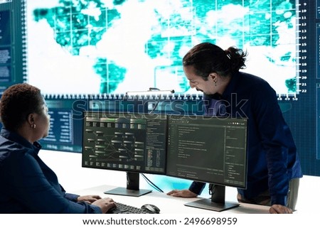 Group of governmental hackers using hacking tools to secure a network, focusing on cyber defense and data protection measures. Experts team examining important information on big screen.