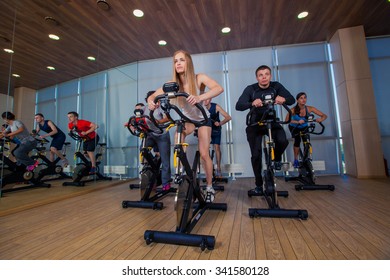 Group Of Gym People On Machines, Cycling In Class.