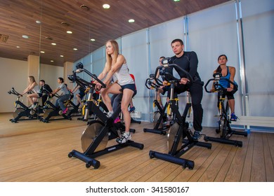 Group Of Gym People On Machines, Cycling In Class.