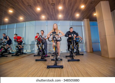 Group Of Gym People On Machines, Cycling In Class.