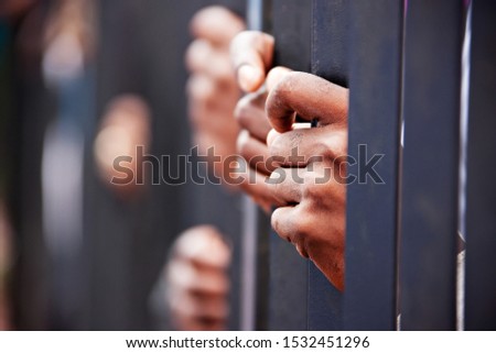 group of hands African people behind bars holding them.
