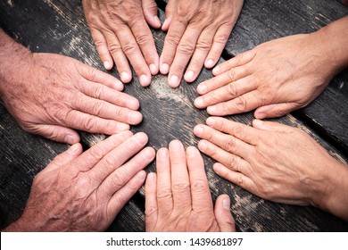 Group Of Hands Touch Each Other Like A Seance. Caucasian People Women And Men. Dark Wooden Table On Background