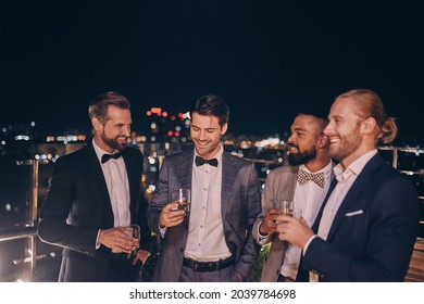 Group of handsome young men in suits and bowties drinking whiskey and smiling - Shutterstock ID 2039784698