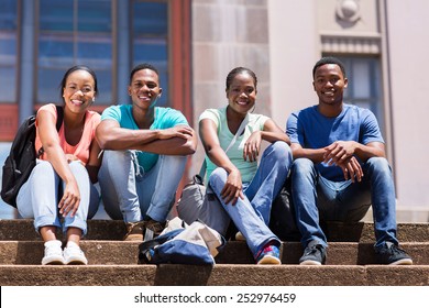 group of happy african student sitting outside college building