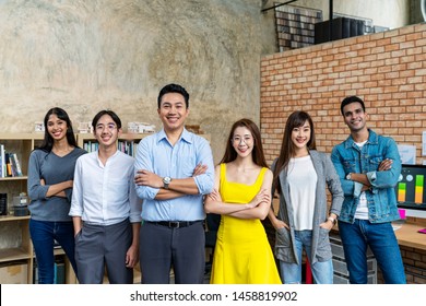 Group Of Happy Asian Employee Are Standing And Looking At Camera With Feeling Confident At Workplace Company. Portait Of Asian Creative Team Posing In Workspace.