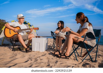 Group of happy Asian friends playing guitar and singing with clapping together having fun and enjoying while camping picnic on the beach in summer vacation. Young male and female party at the seaside. - Powered by Shutterstock