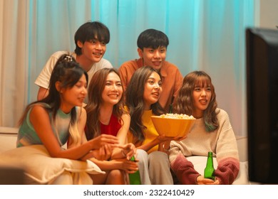 Group of Happy Asian generation z man and woman friends enjoy indoors lifestyle watching movie on television with eating popcorn and drinking beer together in living room at home on holiday vacation. - Powered by Shutterstock