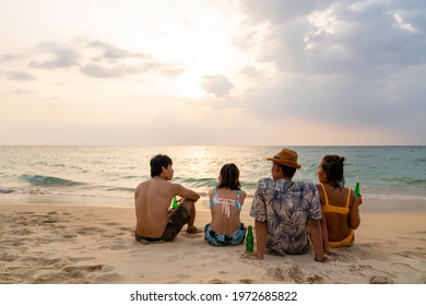 Group Of Happy Asian Man And Woman Friends Sitting On The Beach Enjoy Drinking Beer With Talking Together At Summer Sunset. Male And Female Friendship Relax And Having Fun Outdoor Lifestyle Activity.