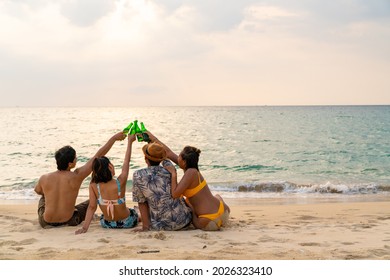 Group of Happy Asian man and woman friends sitting on the beach enjoy drinking beer with talking together at summer sunset. Male and female friendship relax and having fun outdoor lifestyle activity. - Powered by Shutterstock