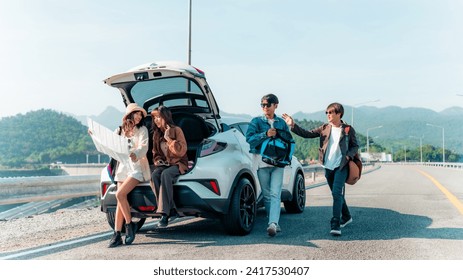 Group of Happy Asian man and woman enjoy and fun outdoor lifestyle road trip travel nature countryside on summer holiday vacation. Generation z people friends sitting on car trunk and looking on a map - Powered by Shutterstock