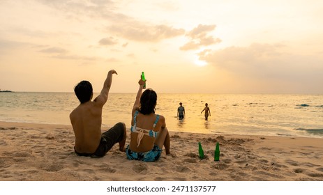 Group of Happy Asian man and woman enjoy and fun outdoor lifestyle travel nature at the sea on summer beach holiday vacation. People friends relaxing and drinking beer together on the beach at sunset. - Powered by Shutterstock