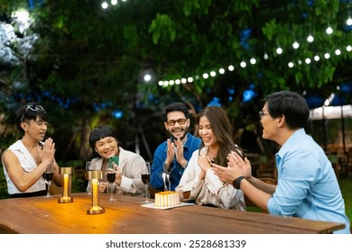 Group of Happy Asian millennial people friends enjoy and fun celebration birthday party at dinner party the garden at restaurant. Beautiful woman excited with birthday cake and blowing candle. - Powered by Shutterstock