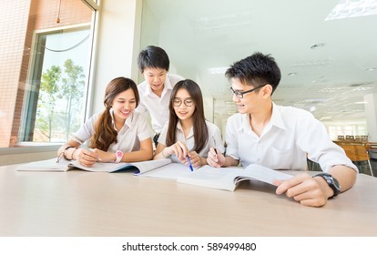 Group Of Happy Asian Student, Discuss, Study And Learn Together As A Friend And Teamwork With Lecture After Computer Class By Using Textbook Or Book In Education Classroom At Library Of University