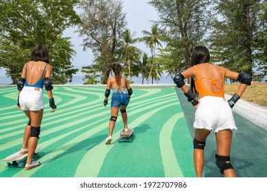 Group Of Happy Asian Woman Friends Skateboarding Together At Skateboard Park By The Beach. Happy Female Friendship Enjoy Summer Outdoor Active Lifestyle Play Extreme Sport Surf Skate At Public Park.