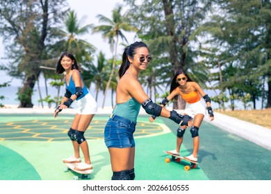 Group Of Happy Asian Woman Friends Skateboarding Together At Skateboard Park By The Beach. Happy Female Friendship Enjoy Summer Outdoor Active Lifestyle Play Extreme Sport Surf Skate At Public Park.