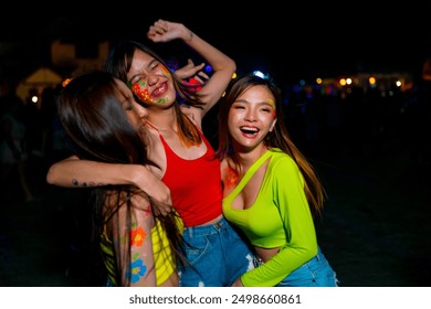 Group of Happy Asian woman friends enjoy and fun outdoor active lifestyle celebrating and dancing together at full moon night party at koh phangan beach, Thailand on summer holiday vacation night. - Powered by Shutterstock