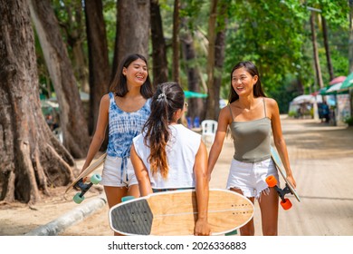 Group Of Happy Asian Woman Girl Friends Carry Skateboard Walking With Talking Together At Skateboard Park. Female Friendship Enjoy Outdoor Activity Lifestyle Play Extreme Sport Surf Skate Together