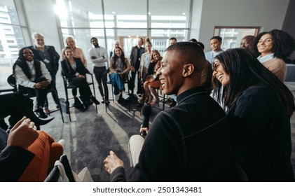 A group of happy and attentive individuals participating in an engaging conference session, showing enthusiasm and connection in a modern setting. - Powered by Shutterstock