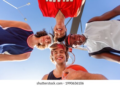 Group Of Happy Basketball Players Putting Their Heads Together In Unity Outdoors, Bottom View. Cheerful Young Sportsmen Getting Primed For Game. Team Work In Sports Concept