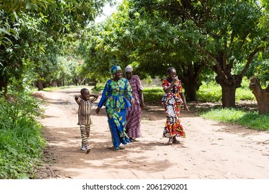 A group of happy black African villagers strolling on a dirt road in a West African neighborhood