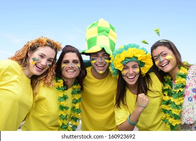 Group of happy brazilian soccer fans commemorating victory, with the flag of Brazil swinging in the air.