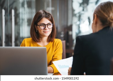 Group Of Happy Business People Have Meeting At Workplace In Office. Two Positive Woman Working Together Using Modern Laptop For Working Concept