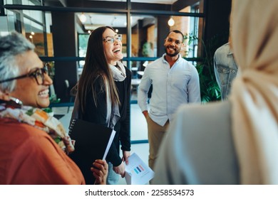 Group of happy businesspeople laughing cheerfully during a staff meeting in a modern office. Multicultural entrepreneurs working as a team in an inclusive workplace. - Shutterstock ID 2258534573