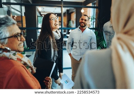 Group of happy businesspeople laughing cheerfully during a staff meeting in a modern office. Multicultural entrepreneurs working as a team in an inclusive workplace.