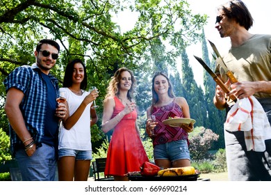group of happy and cheerful young people having fun around barbecue grill during a summer holiday party outdoor in the garden - Shutterstock ID 669690214