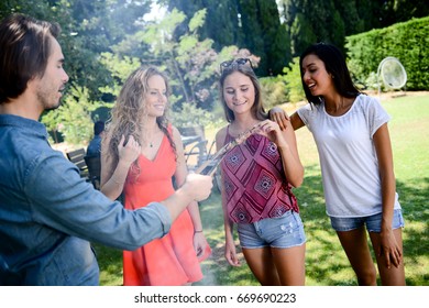 group of happy and cheerful young people having fun around barbecue grill during a summer holiday party outdoor in the garden