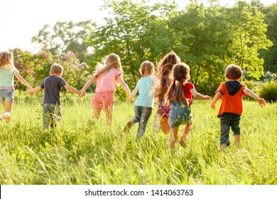 A group of happy children of boys and girls run in the Park on the grass on a Sunny summer day . The concept of ethnic friendship, peace, kindness, childhood - Shutterstock ID 1414063763