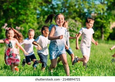 A group of happy children of boys and girls run in the Park on the grass on a Sunny summer day - Powered by Shutterstock