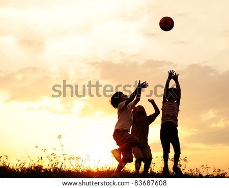 Group of happy children playing with ball on meadow, sunset, summertime