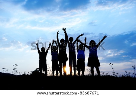 group of happy children playing on meadow, blue sky, summertime