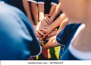 Group Of Happy Children In Sports Team Stacking Hands Outdoor In A Summer Day. Children Team Sports. Boys At Sports Camp Stacking Hands Before A Game. School Age Children In A Team At The Grass Field