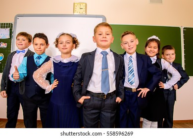 Group of happy classmates in school uniform posing together at a classroom. Education.